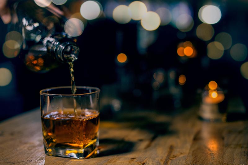 glass of whiskey and ice on wooden table